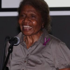 Catherine Davani, a dark skinned woman and PNG's first female judge stands at microphone giving a speech