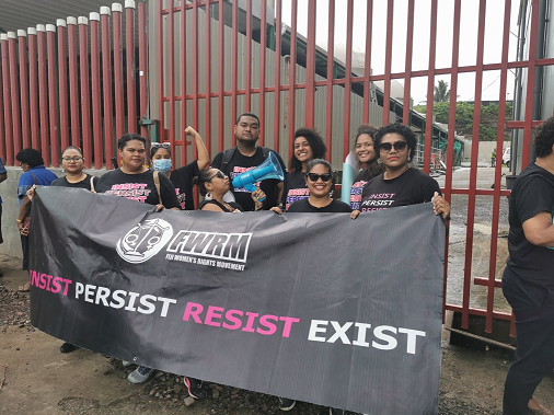 A group people stand with a large banner that says: Insist Persist Resist Exist