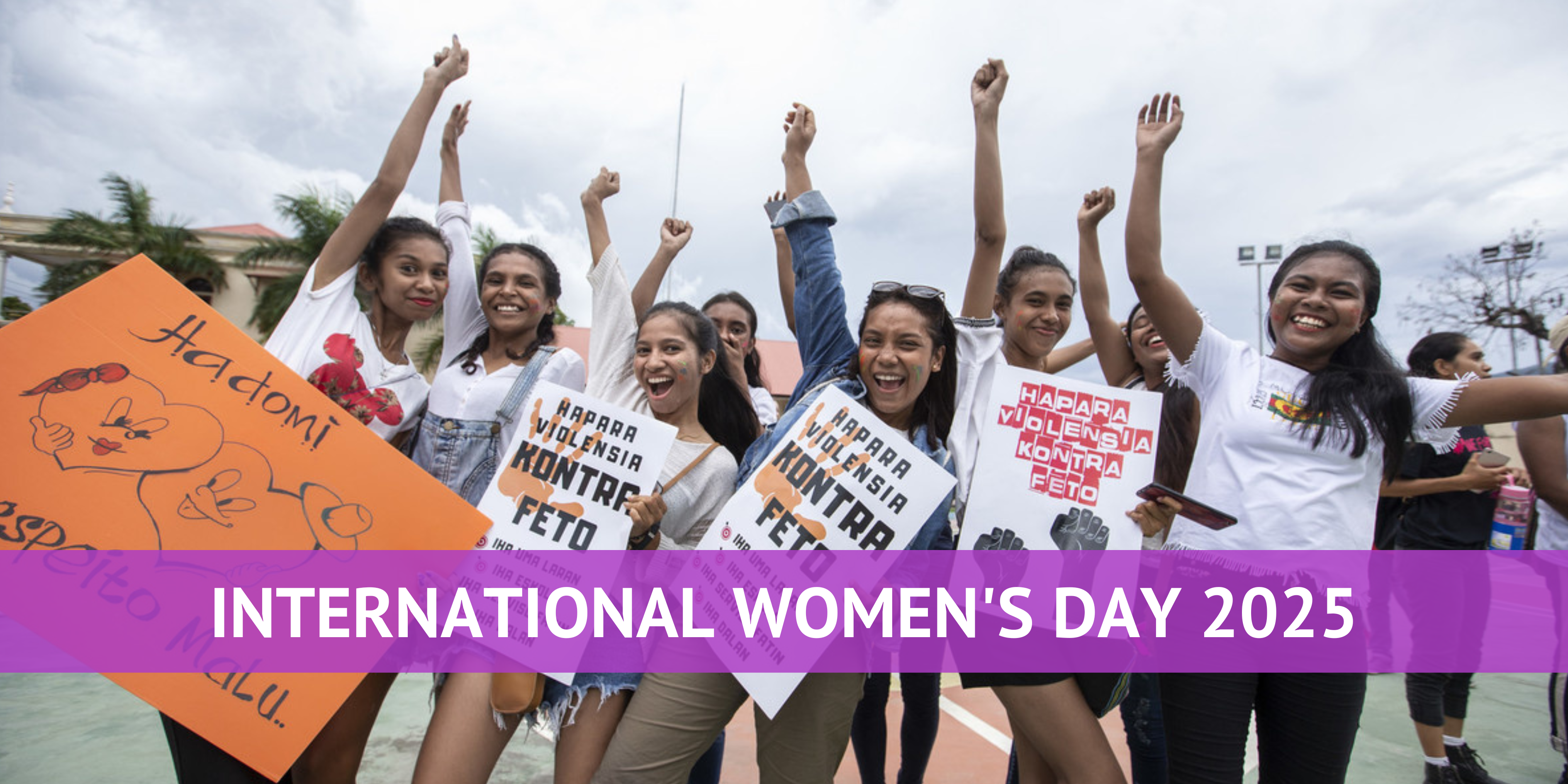 International Women's Day 2025 - Women gather together with signs, raising their fists in the air