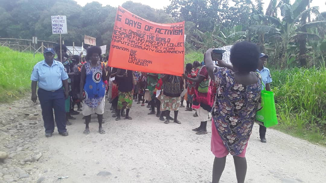 A person is taking a photo of a big group standing with a bright banner