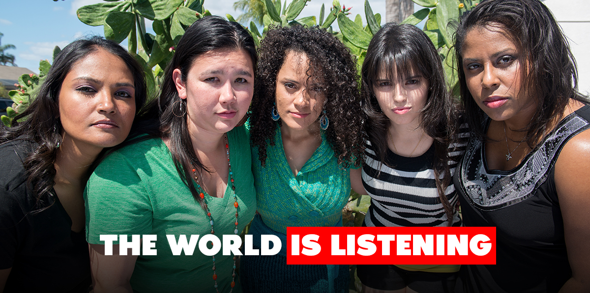 Five women of diverse ethnicities link arms and lean forward to look into the camera. Text reads: The world is listening
