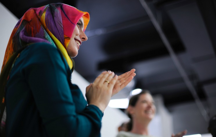 Image of a woman clapping and looking to the right