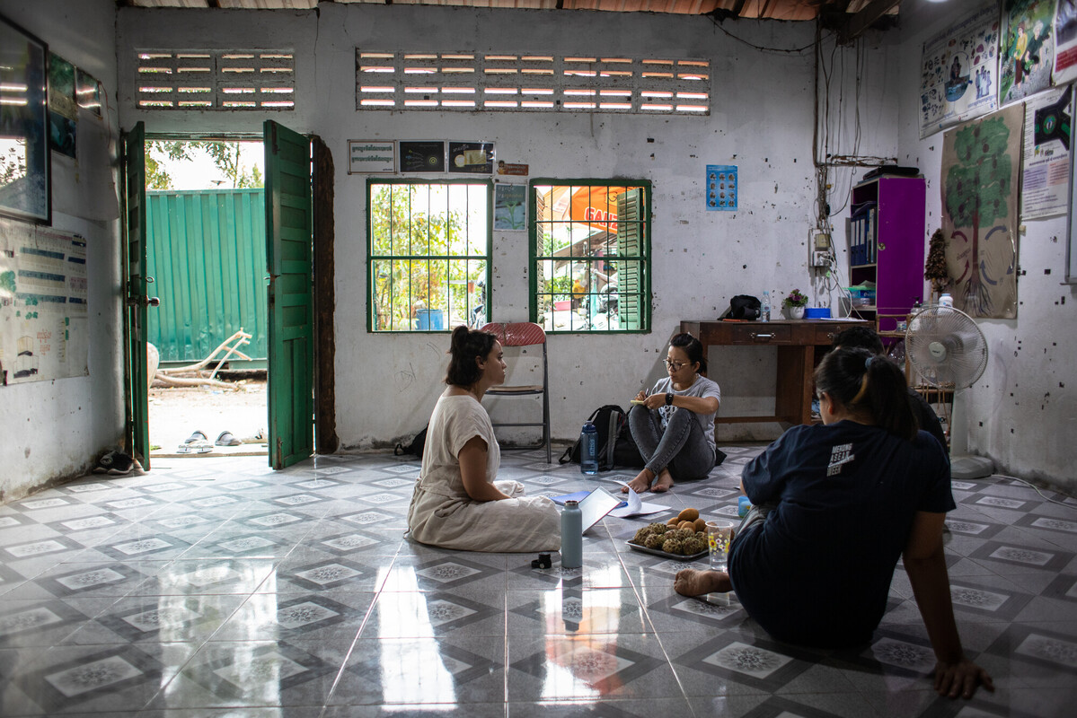 3 women and a third obscured person sit in a circle on the floor of the Workers Information Centre in Cambodia