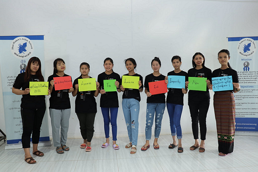 A group of people stand holding signs for 16 days of activism.