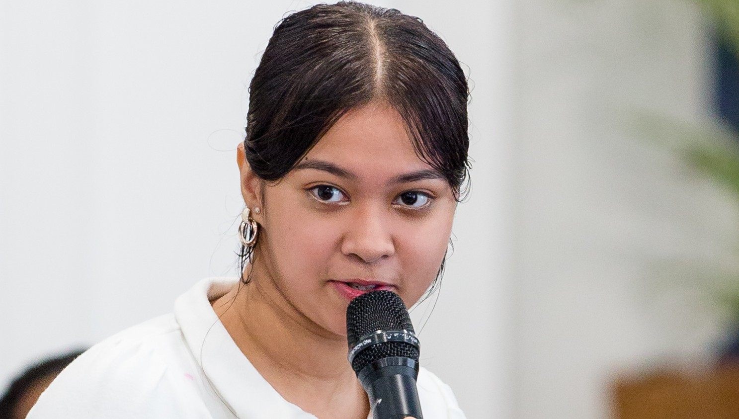 A young girl is standing and holding a microphone 