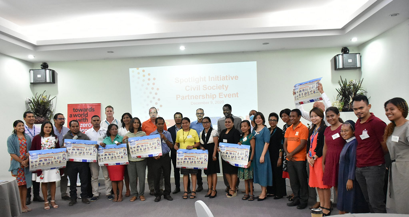 A group of people in a meeting stand with large signs