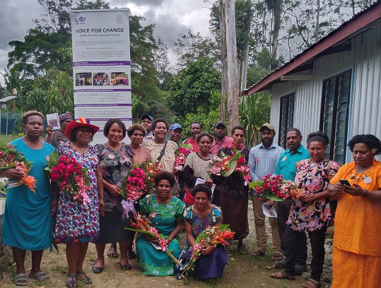 A smiling group of people hold bouquets of flowers.