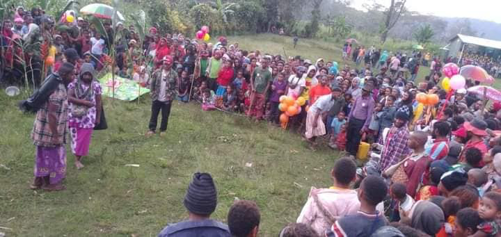 A group of people stand in a circle listening to speakers