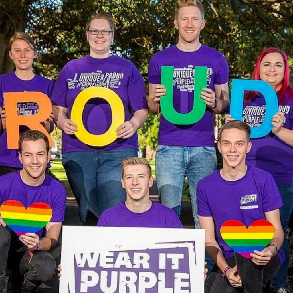 Image of young people wearing purple and a sign reading: "proud"