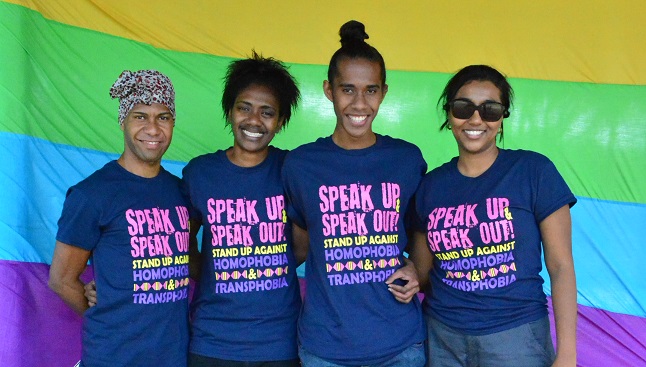 FWRM supporters stand in front of a rainbow flag.