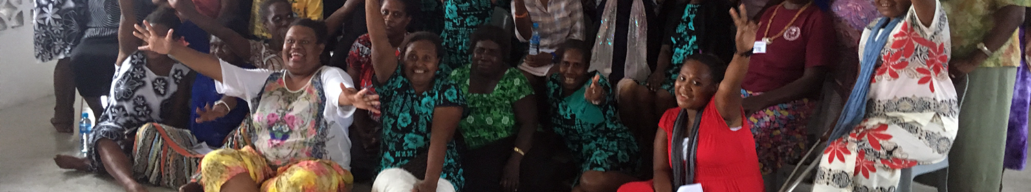 Image of woman sitting in a group in Solomon Islands, looking at the camera.