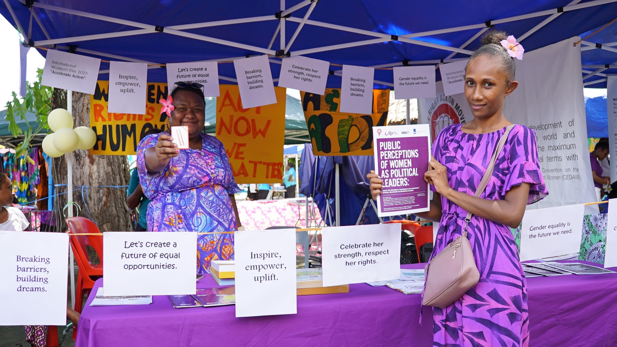 Women's Rights Action Movement staff, including Bezel Aonima, pose together at the booth showcasing WRAM's work to advance women's rights in Solomon Islands.