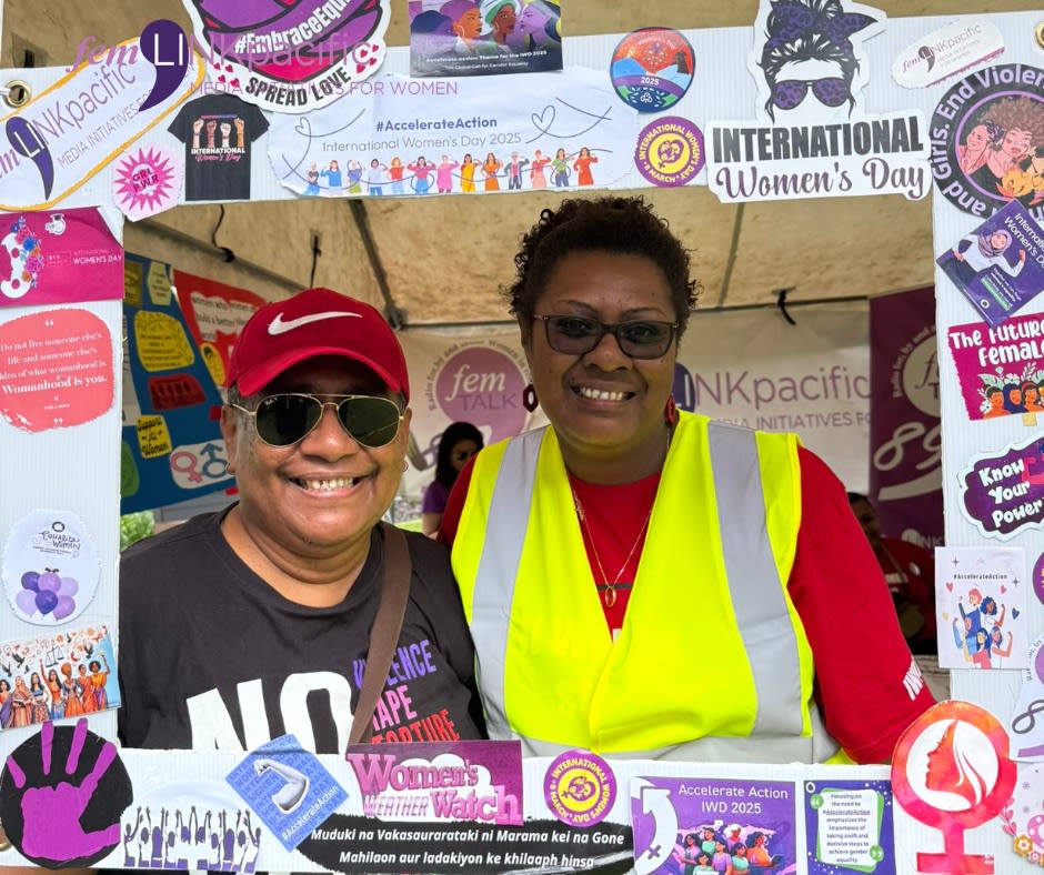 Two women, one of which is femLINKpacific's Executive Director Fay Volatabu, are posing together with a photo frame as they smile at the camera.
