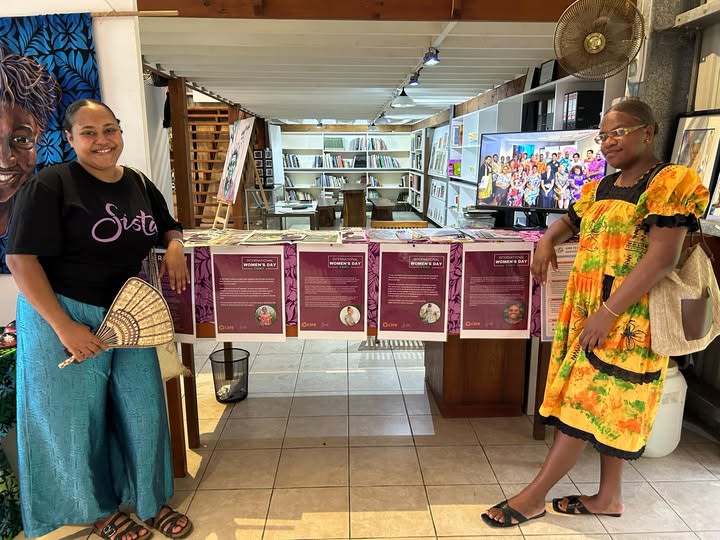 Two Sista staff members pose together at a booth showcasing the organisation's work.