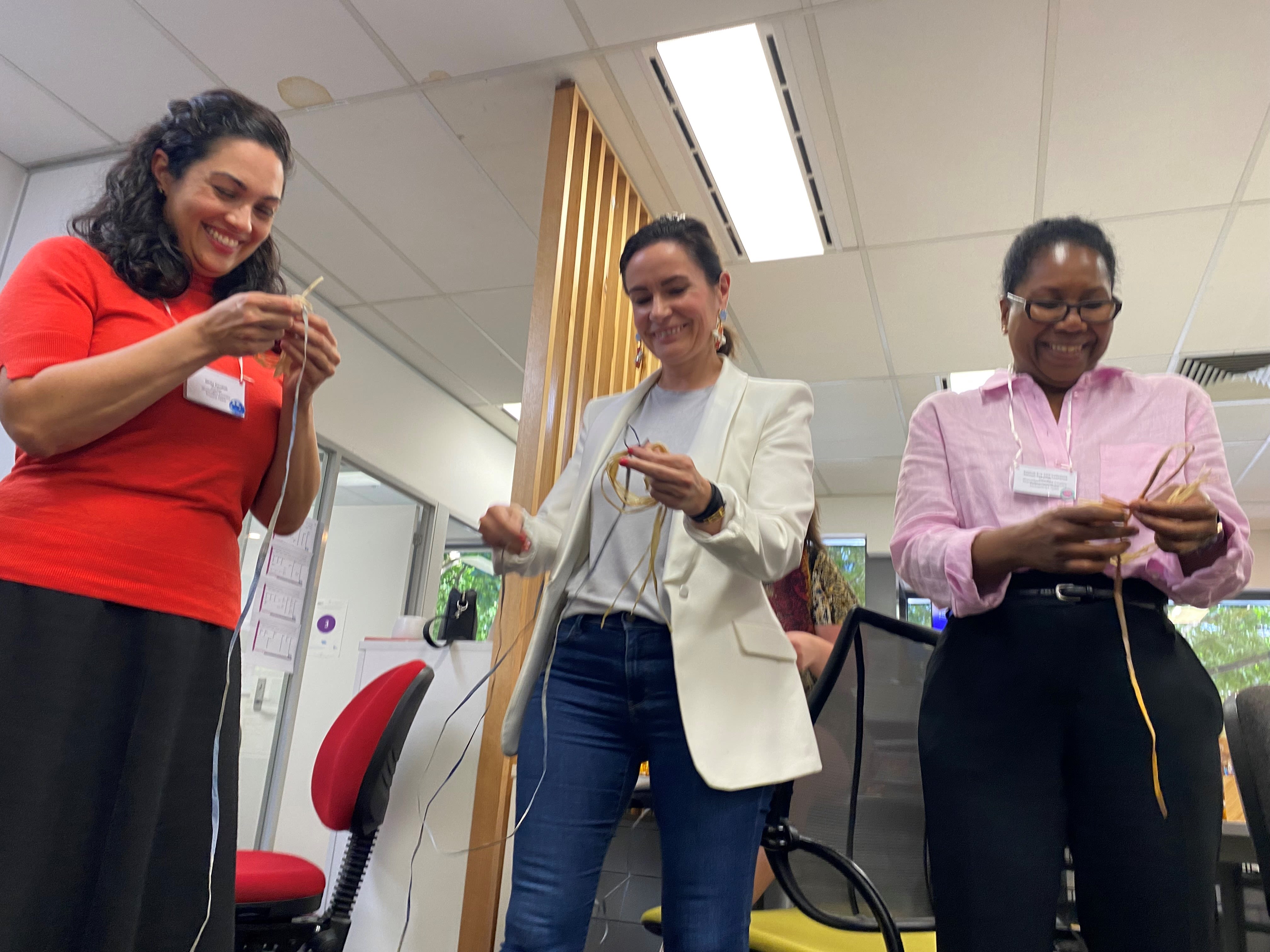 Bettina and Salmah laughing together as they take part in a weaving activity at the IWDA office.