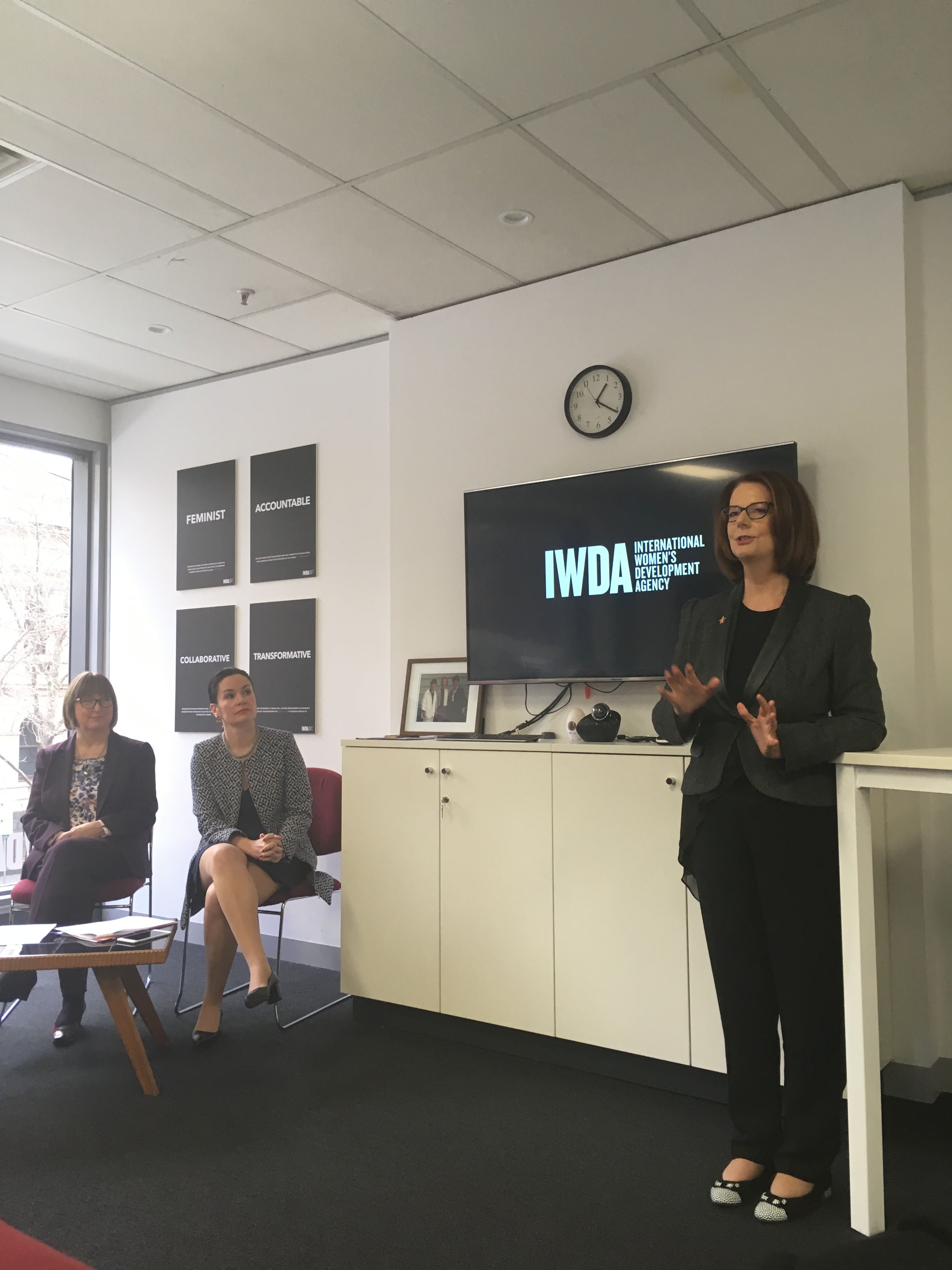 Bettina is seated in one of IWDA's meeting rooms as she watched Julia Gillard address the room. Above them are the IWDA logo and values.