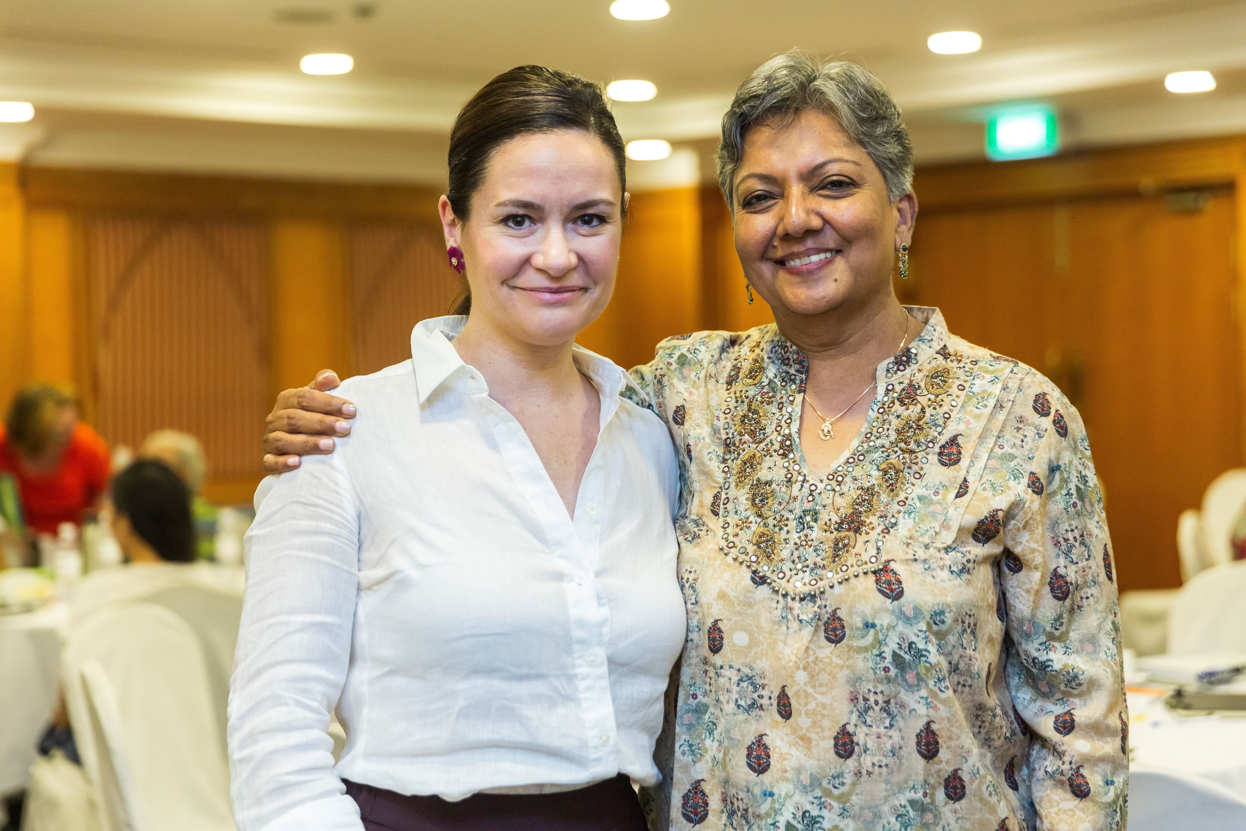 Bettina and Srilatha Batliwala have their arms around each other as they smile for the camera.