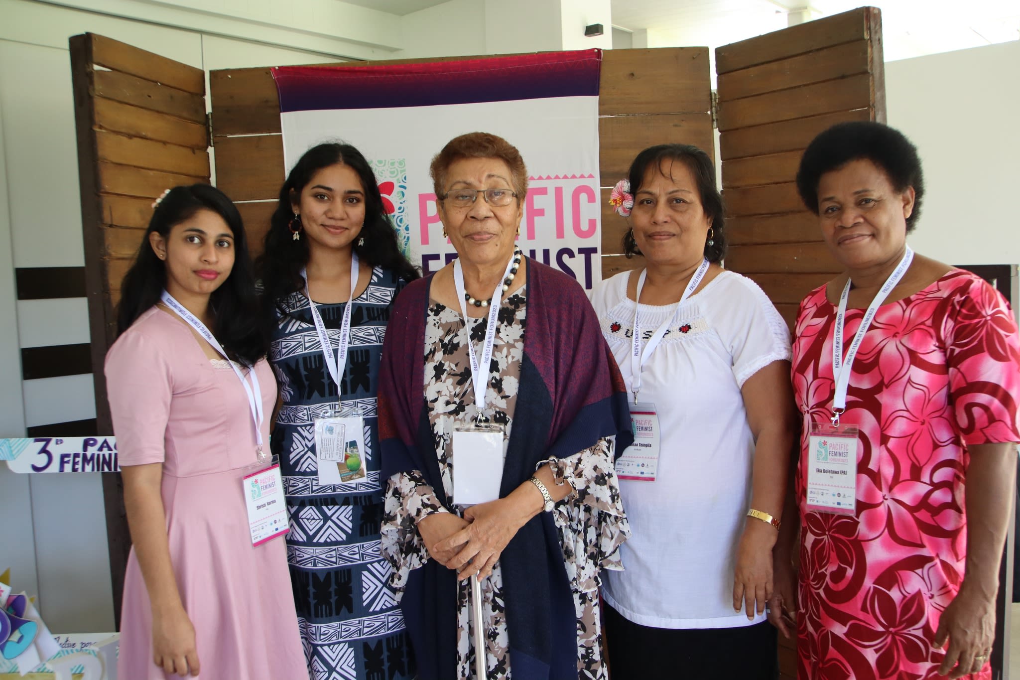 Five women are posing together in from of a sign that reads 'Pacific Feminist Forum'.