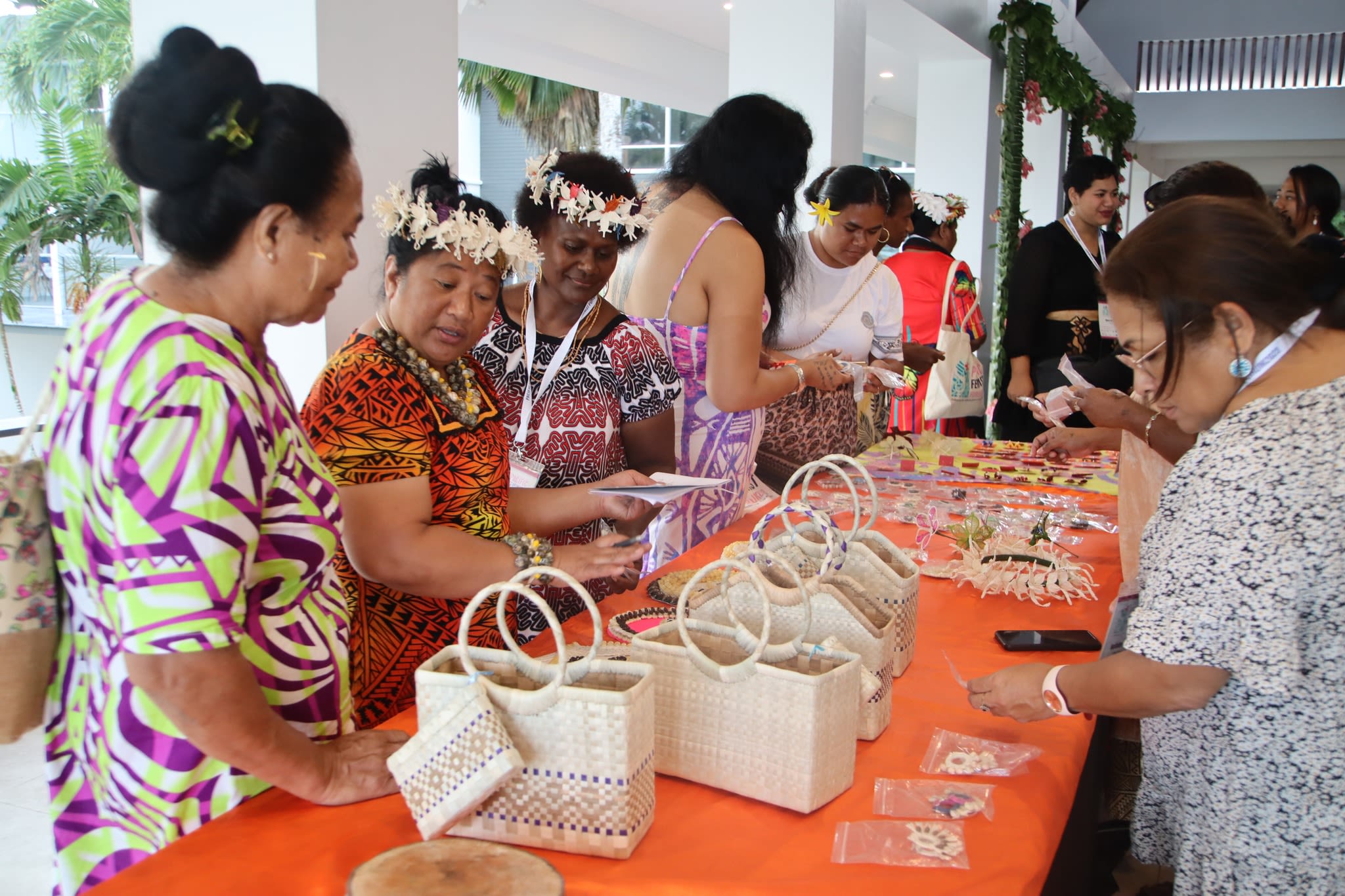 Participants at the 3rd Pacific Feminist Forum are browsing a table full of handicrafts including woven baskets and handmade jewellery. 
